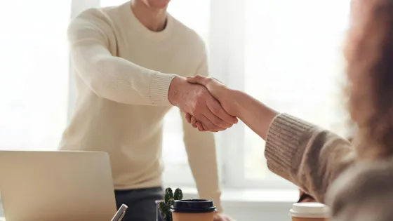 Twee mensen schudden handen tijdens een sollicitatiegesprek